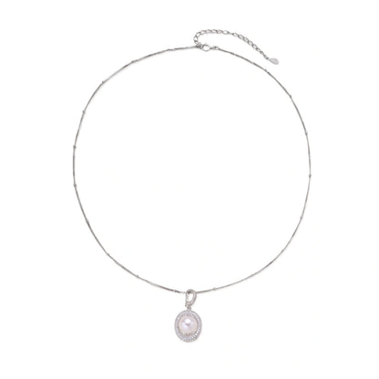 Oval sterling silver pendant with crystal halo surrounding a white freshwater pearl on delicate chain