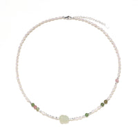 Delicate pearl necklace with pale green serpentine jade centerpiece and colorful agate beads on cream background
