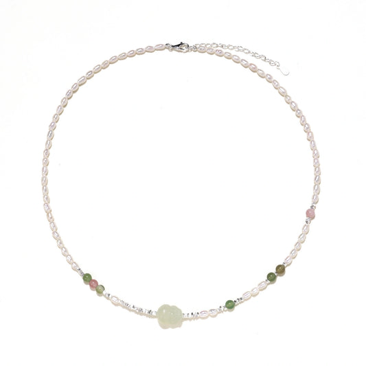 Delicate pearl necklace with pale green serpentine jade centerpiece and colorful agate beads on cream background
