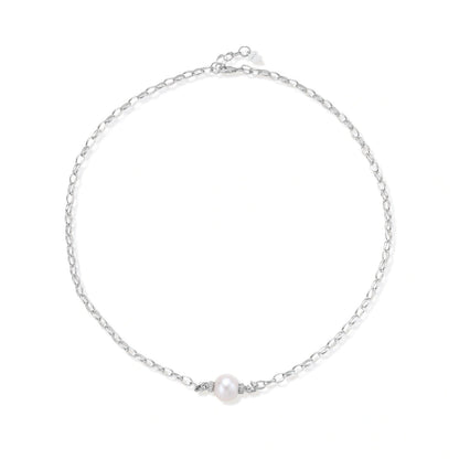 Dainty rhodium-plated silver chain necklace with centered 10mm freshwater pearl and crystal accents on cream background