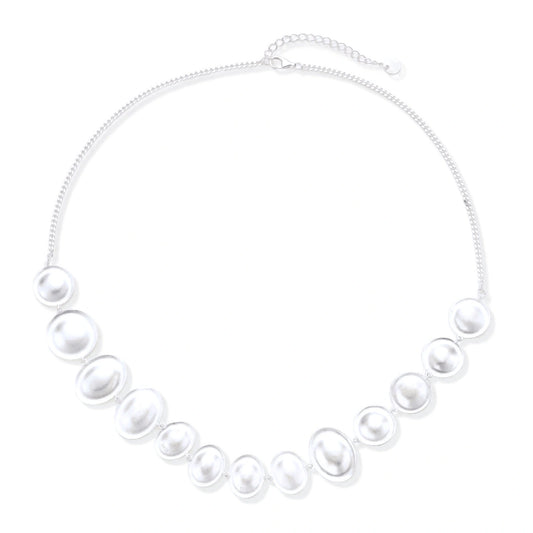 Graduated pearl-finish silver discs forming an organic bubble bib necklace on delicate chain against cream background.
