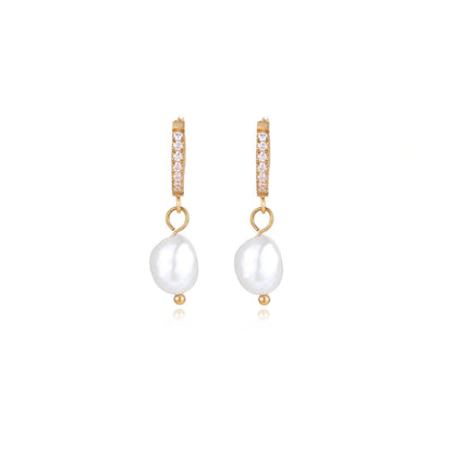 Gold huggie hoop earrings with pavé crystals and white freshwater pearl drops on cream background