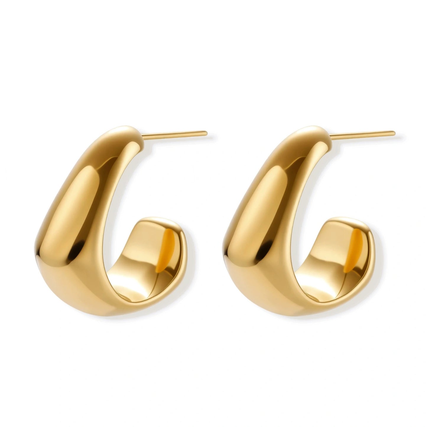 Close-up of curved gold-plated huggie earrings with sculptural design on white background, showing polished finish.