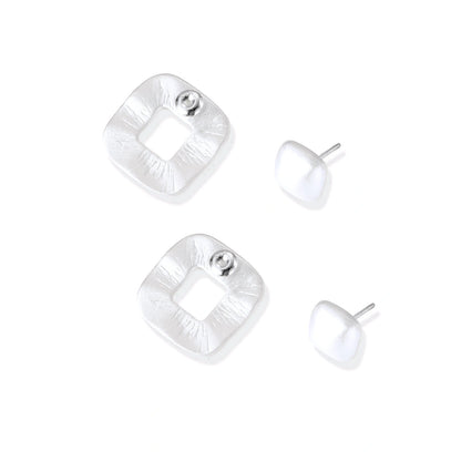 Pair of geometric sterling silver earrings with frosted square frames and glossy rounded studs on white background